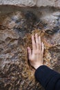 A pilgrim blesses a cross with Jesus hand print, in Via Dolorosa station 5