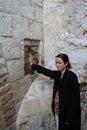 A pilgrim blesses a cross with Jesus hand print, in Via Dolorosa station 5