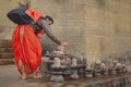 A pilgrim dressed in red doing its prayers at lingams on the river Ganges in Varanasi, India