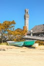 Pilgrim Monument in Provincetown Cape Cod USA jutting into sky beside weathered buildings and boats pulled up on the beach Royalty Free Stock Photo