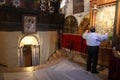 A pilgrim prays in front of the pictures of the Virgin with the Child Jesus, near the entrance to the cave of Jesus` birth, Bethle Royalty Free Stock Photo