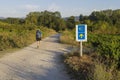 Pilgrim walking alone passing by a yellow shell and arrow sign that guides the pilgrims along the Camino de Santiago, Spain.