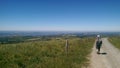 Backpaker woman walking on a dirt road, amazing view on french contryside.