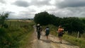 Pilgrims with backpacks, walking on a dirt road.