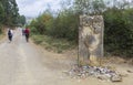 Pilgrims passing by a sign totem waymark made in stone that guides the pilgrims along the Camino de Santiago, Spain.