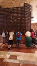 Pilgrims praying in front of the tomb of Saint Francis, in Assisi