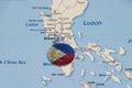 Pilipino flag on the coin of Philippine one peso money on the map near Manila city. Concept of finance or travel Royalty Free Stock Photo