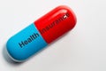 A pill in blue and red as a smbol photo has the words  Health Insurance on it. The pill is isolated against a white background Royalty Free Stock Photo