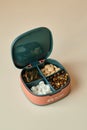 Pill box contains four different types of pills. Pillbox lies on beige background. Compact box to carry pills with you
