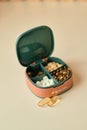 Pill box contains four different types of pills. Pillbox lies on beige background. Compact box to carry pills with you