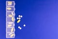Pill box with days of the week and different pills on a blue background. Copy space. Royalty Free Stock Photo