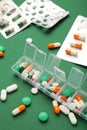 Daily pill box with medications and nutritional supplements on green background. Vertical photo Royalty Free Stock Photo