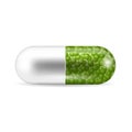 A pill in the capsule shape with the green granules inside it. Royalty Free Stock Photo