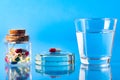 pill and a glass of water on a glassy blue table. Reflection in glass. close-up. Space for text. The concept of treatment and