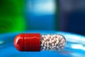 Pill on a glassy blue table. Reflection in glass. Close-up. Space for text