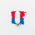Pill on red and blue paint brush strokes