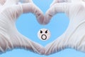 Pill with a screaming smiley inside a heart from hands in medical gloves on a blue background.Painkiller concept Royalty Free Stock Photo