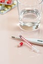 Pill, syringe and thermometer on a beige pastel background