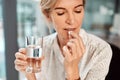 Pill, water and senior woman drinking medicine or supplements for illness or health care in her office. Medical, drugs Royalty Free Stock Photo