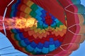 A pillar of flame from a gas burner inflates a huge multi-colored balloon
