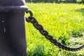 pillar with iron chain on grass background. industrial, nature.