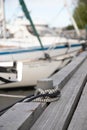 Pillar for tying boats on a wooden pier. Bollard with two ropes on the pier fishing boats. in the background blurred boats and