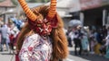 Man dressed as a red and white devil with brown hair dancing in the Diablada Pillarena parade in the city of Pillaro - Ecuador