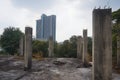 Pillars of an unfinished abandoned building in Thailand and a large condominium building can be seen in the background. Royalty Free Stock Photo