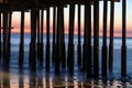 Pillars of Ventura Pier at Sunset. Beach, smooth blue ocean; colored sky in background.