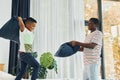 Pillow fight. African american father with his young son at home