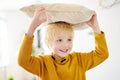 Pillow fight. Mischievous preschooler child jumping on a sofa and hitting with pillows.Active games for child at home Royalty Free Stock Photo