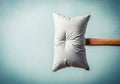 A pillow pierced by a wooden hammer handle. Space for text. Royalty Free Stock Photo