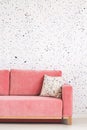 Pillow on pink sofa against patterned wallpaper in bright living