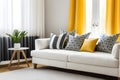 Pillows with geometric pattern lying on a white sofa in cozy living room with yellow curtains Royalty Free Stock Photo