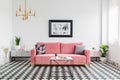 Pillows on pink sofa in spacious living room interior with check