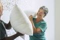 Pillows war at home for caucasian couple of playful adult senior man and woman play in the bedroom at the morning. hapiness and