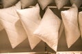 Pillows of white color suspended on a crossbeam in rows. Household items, light industry