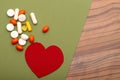 Pills background.Many bright pills and red heart on a green background.