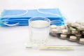 Pills in blister packs glass of water, thermometer and medical mask on white. Health concept. Royalty Free Stock Photo