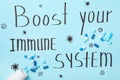 Pills on light blue sheet of paper with words Boost Your Immune System, flat lay