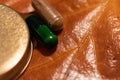 Pills and a bottlecap on a brown leaf