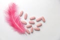 Pills that bring relief. A pink feather next to the pills. Royalty Free Stock Photo