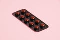 Pills in brown blister pack on pink paper background with copy space. Royalty Free Stock Photo