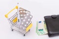 Pills and Capsules in a Shopping Cart and Black Wallet with Euro Money