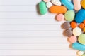 Pills and colored capsules on a neutral striped background.