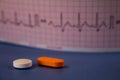 Pills of colors in a neutral background. Electrocardiogram strip out of focus