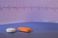 Pills of colors in a neutral background. Electrocardiogram strip out of focus
