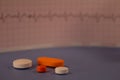 Pills of colors in a neutral background. Electrocardiogram strip out of focus