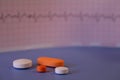 Pills of colors in a neutral background. Electrocardiogram strip out of focus