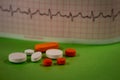 Pills of colors in a neutral background. Electrocardiogram strip out of focus